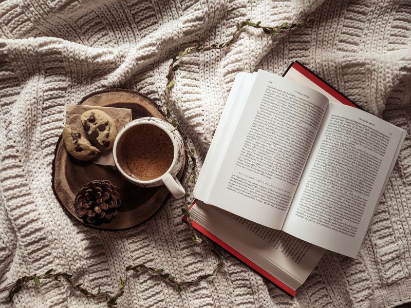 Lesen Ein aufgeschlagenes Buch und eine Kaffeetasse