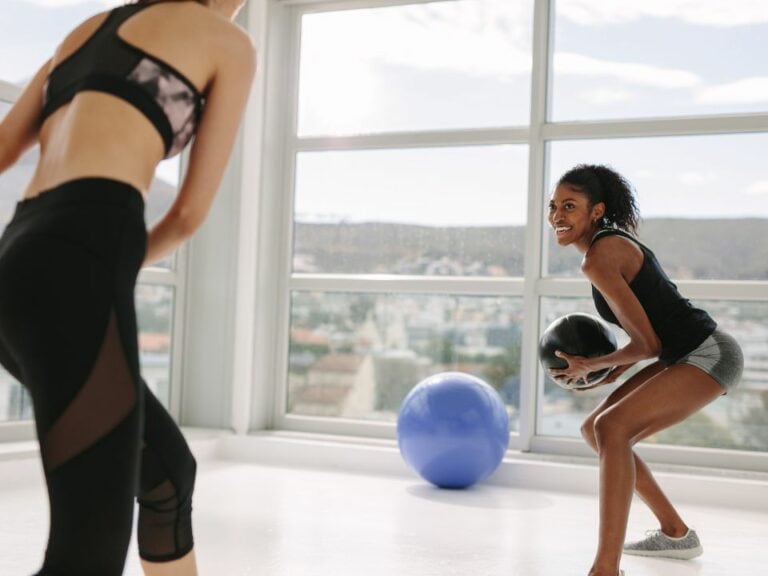 Dynamax-Training. Dynamisches Krafttraining mit Spaßfaktor. Zwei Frauen, die sich einen Dynamax-Ball zuschupfen