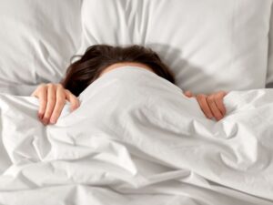 Frau, die sich unter der Decke einigelt